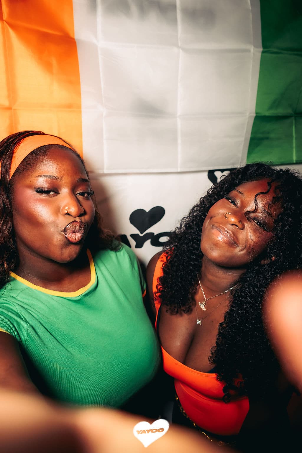 Deux participantes devant le drapeau ivoirien au photocall de YAYOO #5 Babi Era
