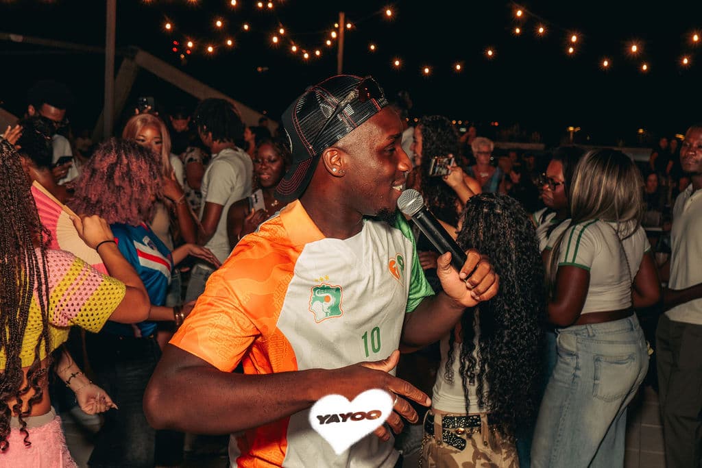 Un MC au micro au milieu du public sur un rooftop YAYOO